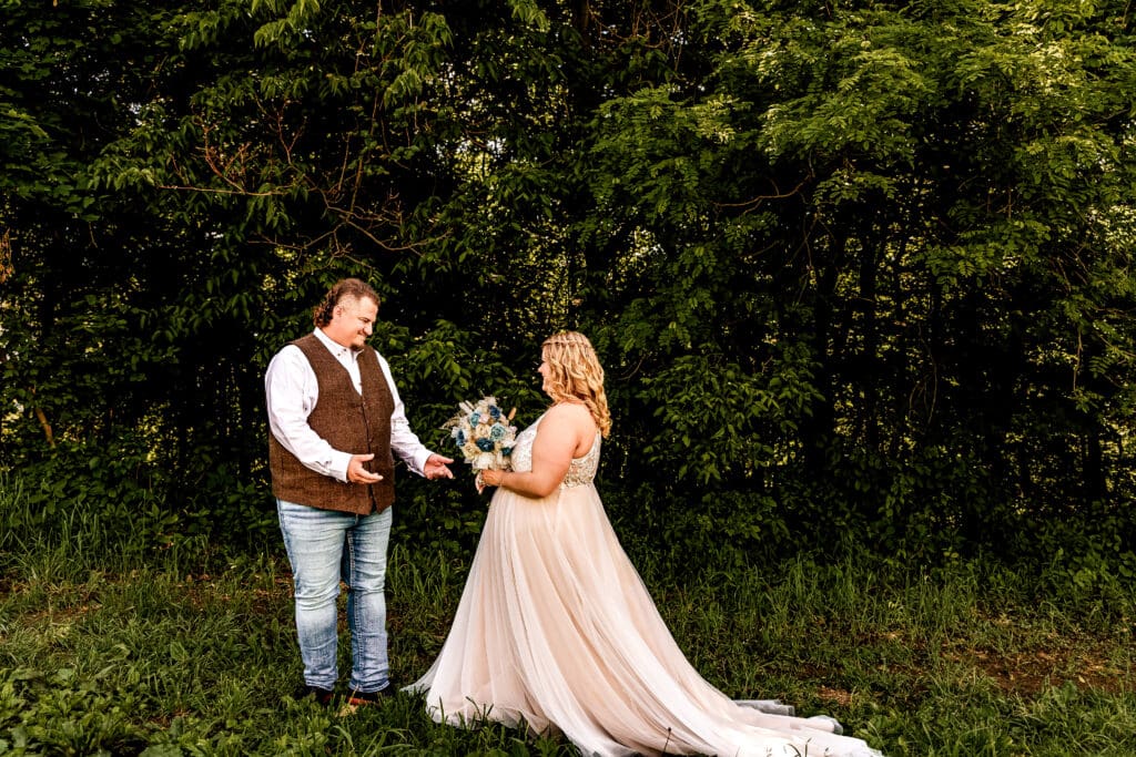 Newlywed couple sharing an emotional first look moment in a field at their family farm in Monongahela, Pennsylvania