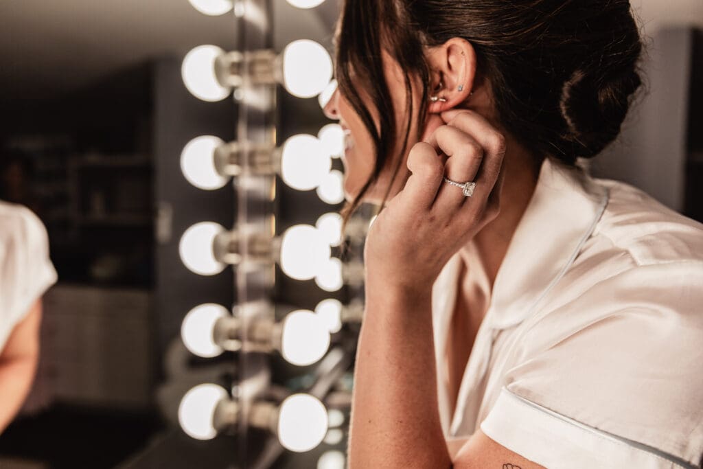 Close-up of engagement ring as bride adjusts her earring in the Willowbrook bridal suite in Volant, Pennsylvania