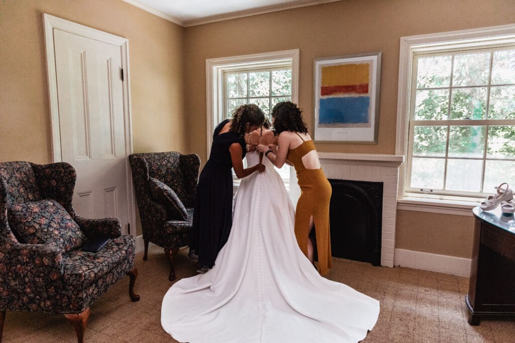 Bridesmaids helping bride into wedding dress at Succop Nature Park