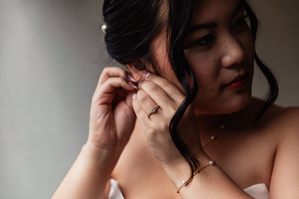 Close up portrait of bride putting on earrings at Sheraton Station Square