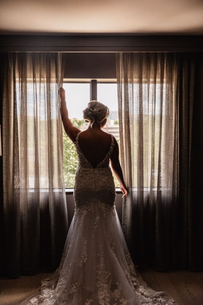 Bride posing with her back to the camera in front of hotel window at Pittsburgh Airport Marriott