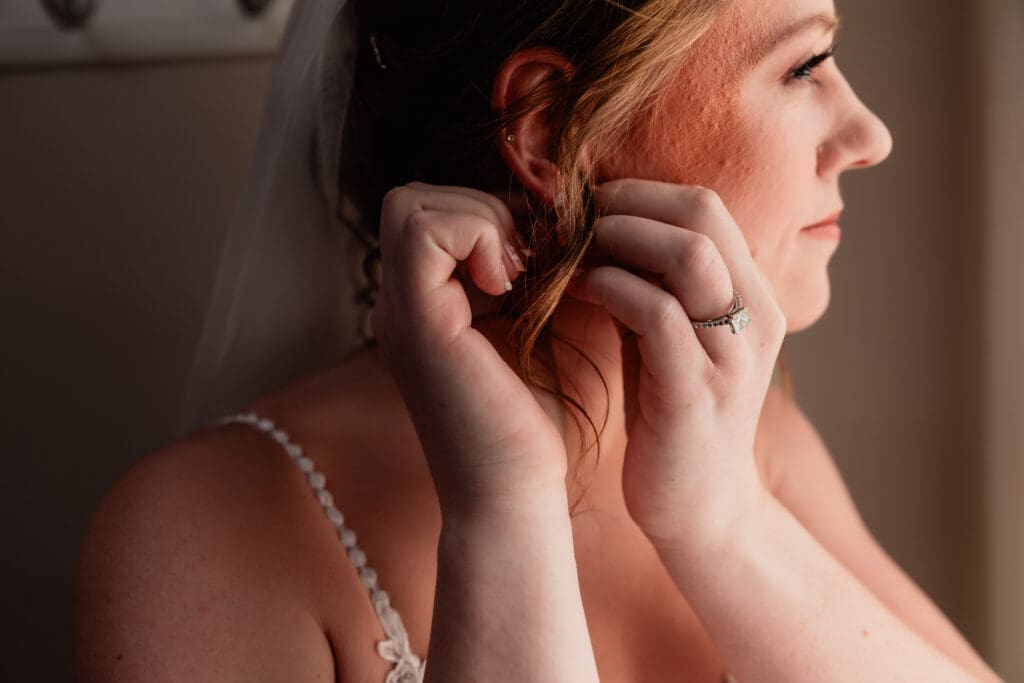 Close-up of bride putting on earrings in the bridal suite at The Barn at Ever Thine in Butler County, PA