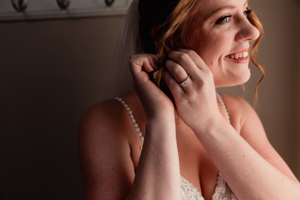 Close-up of bride adjusting her earrings in the bridal suite at The Barn at Ever Thine in Fenelton, Pennsylvania