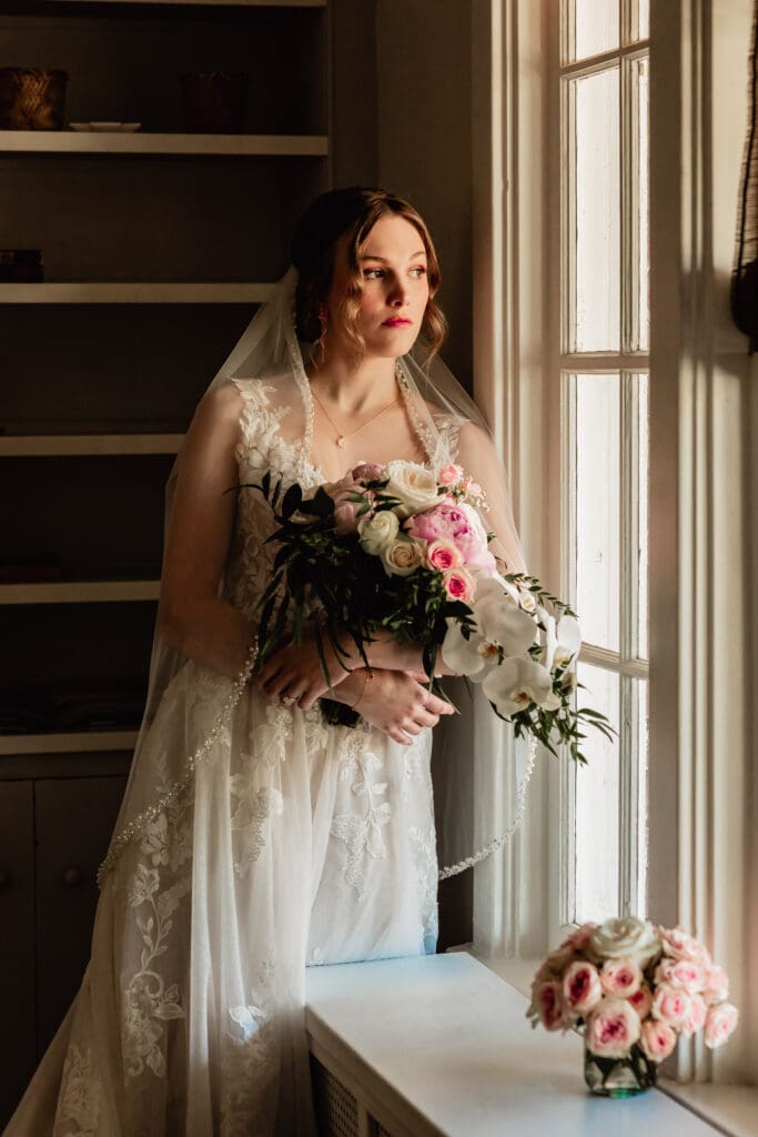 Pittsburgh bride leaning against a window of her Airbnb and gazing out at the street before her Phipps Botanical Gardens wedding