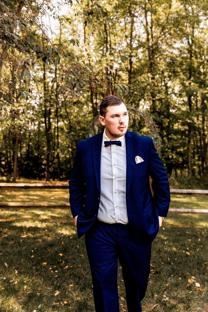 Groom walking and looking off into the distance during wedding portraits at The Barn at Ever Thine in Fenelton, Pennsylvania