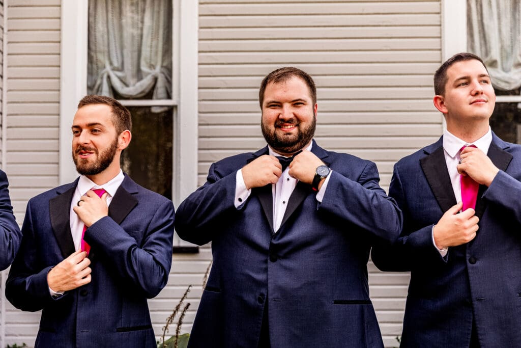 Close up of groom adjusting his tie while getting ready at The Gathering Place at Darlington Lake