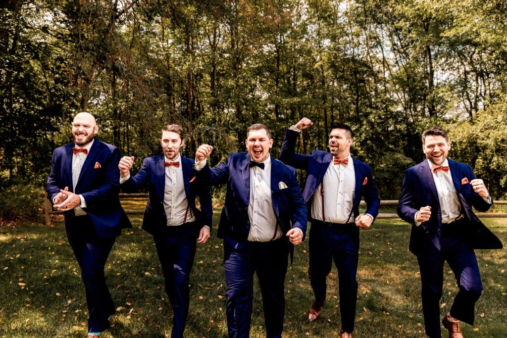 Groom and groomsmen cheering and laughing while walking at The Barn at Ever Thine wedding in Butler County, PA