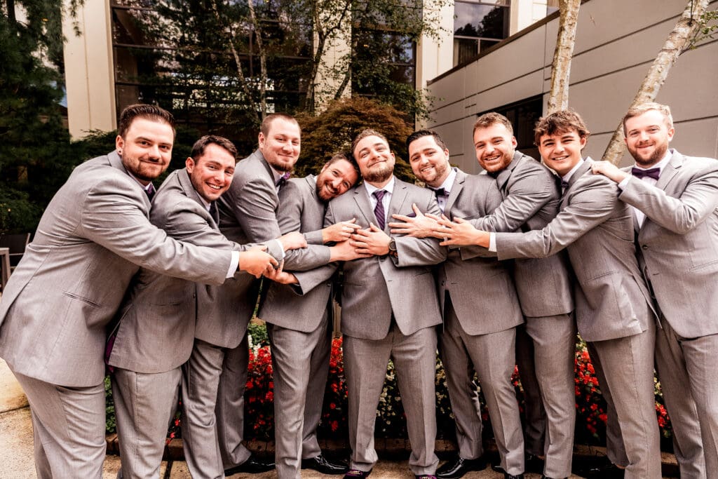Groom and groomsmen laughing and embracing during portraits at Pittsburgh Airport Marriott