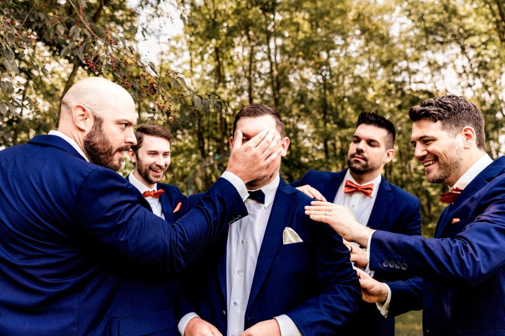 Groomsmen laughing while helping the groom get ready at The Barn at Ever Thine in Butler County, Pennsylvania