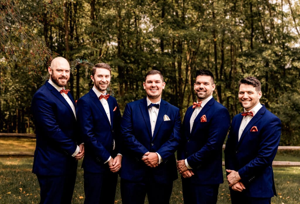 Groom and groomsmen smiling at the camera during wedding portraits at The Barn at Ever Thine in Butler County, Pennsylvania