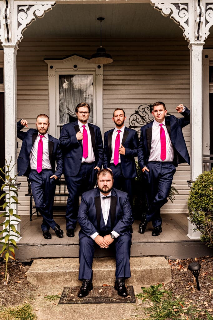 Groomsmen standing behind seated groom on Airbnb porch before wedding at The Gathering Place at Darlington Lake