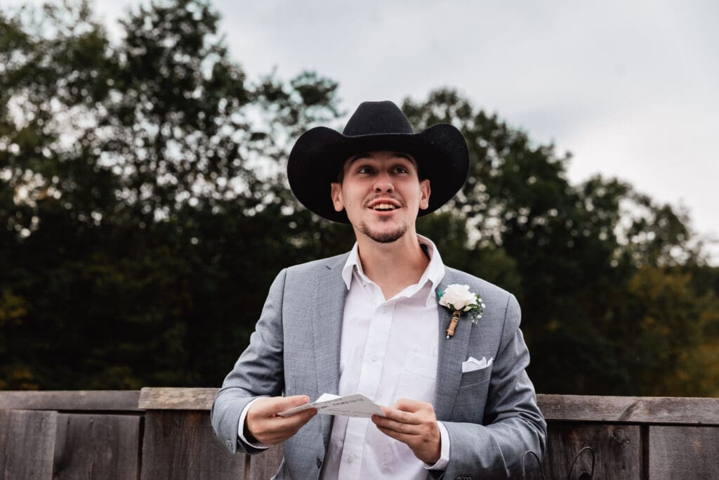 Groom smiling while opening wedding gifts from bride at Hinckston Run Farm