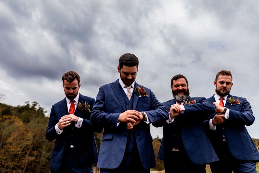 Groom and groomsmen adjust cufflinks on path at Hinckston Run Farm