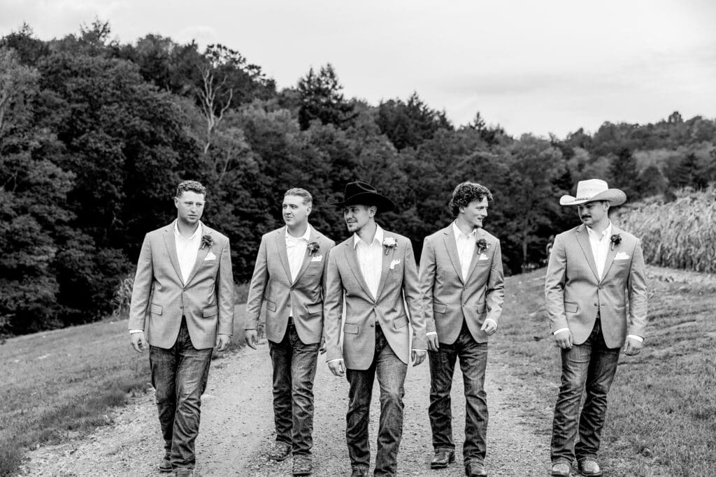 Black and white panoramic photo of wedding party walking together in grassy field at Hinckston Run Farm
