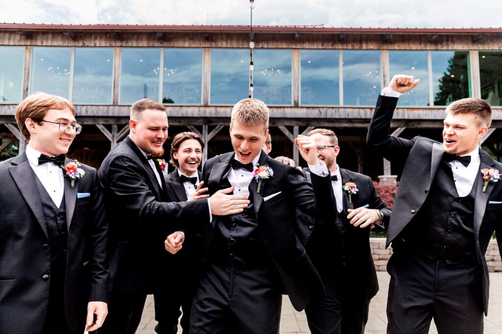 Groomsmen celebrate with raised hands outside a Willowbrook venue
