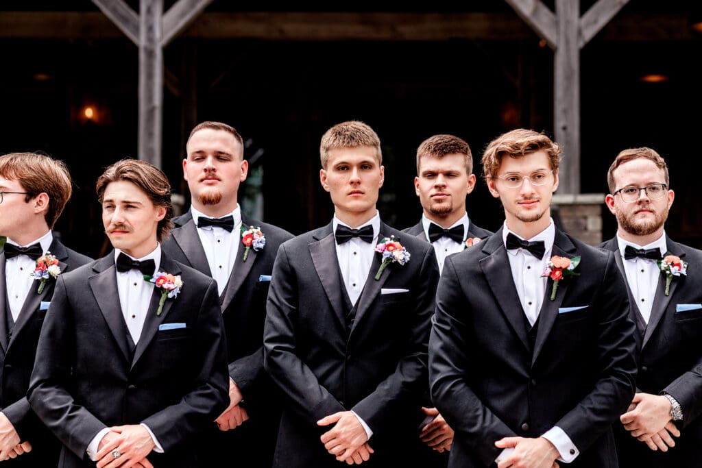 Groomsmen pose against wooden beams at a Willowbrook wedding