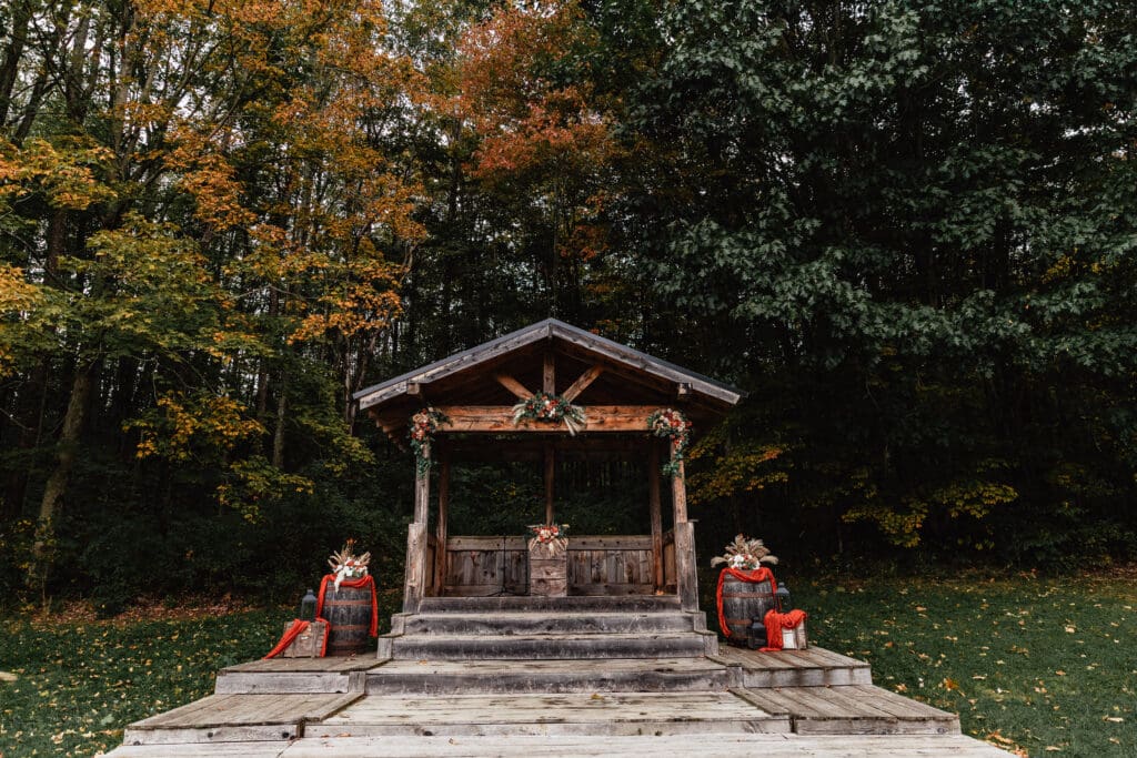 Rustic wooden shelter decorated with pampas grass and boho decor in an autumn forest at Hinckston Run Farm wedding