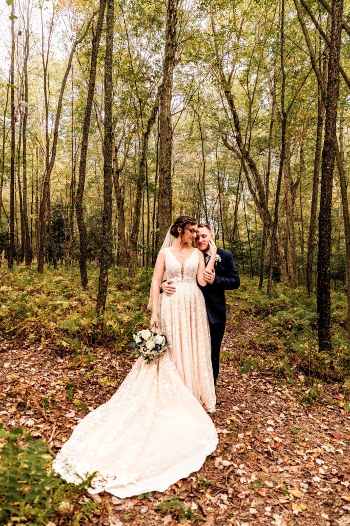 Wedding couple embrace and bride caresses groom’s face in fern field at Pinehall at Eisler Farm