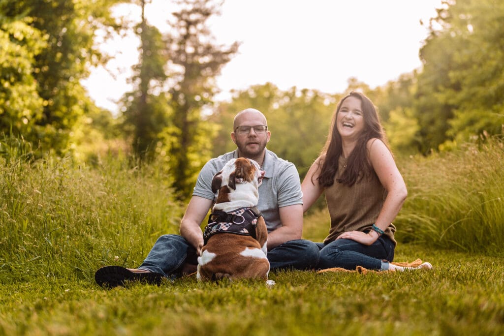 Couple poses while sitting with their bulldog during a fun and casual engagement photography session