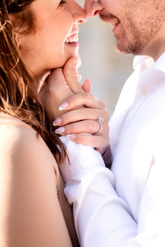Close-up romantic portrait of a couple sharing an intimate moment with soft lighting and white attire during an engagement session