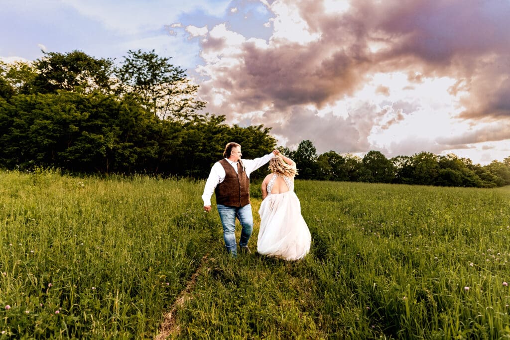 Bride and groom dancing together in a field at their family farm wedding in Monongahela, PA during golden hour