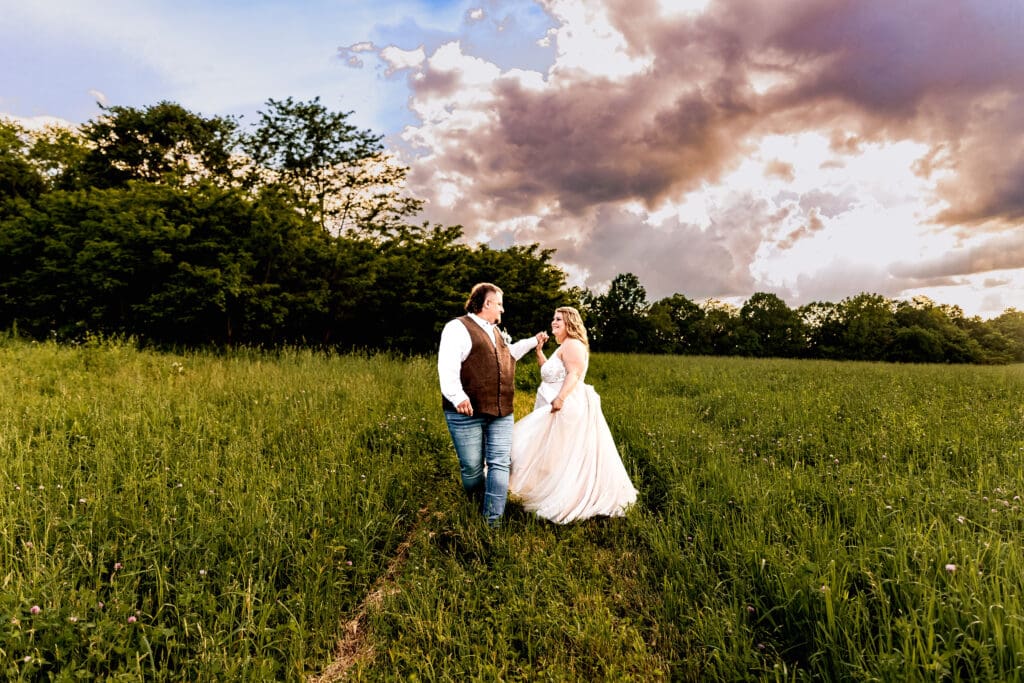 Newlyweds twirling and dancing in an open field at their family farm wedding in Monongahela, Pennsylvania