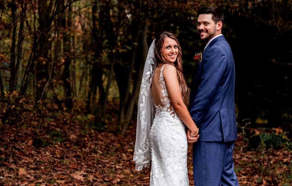 Couple holds hands in autumn forest during Hinckston Run Farm wedding