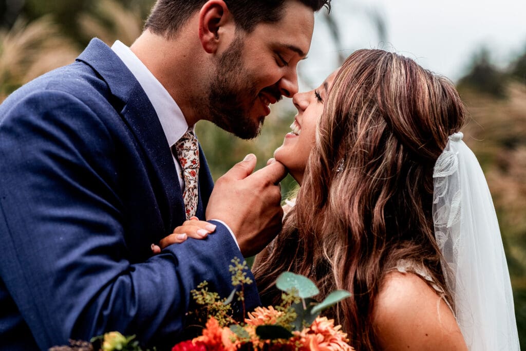 Couple shares intimate moment with red flowers and veil at Hinckston Run Farm