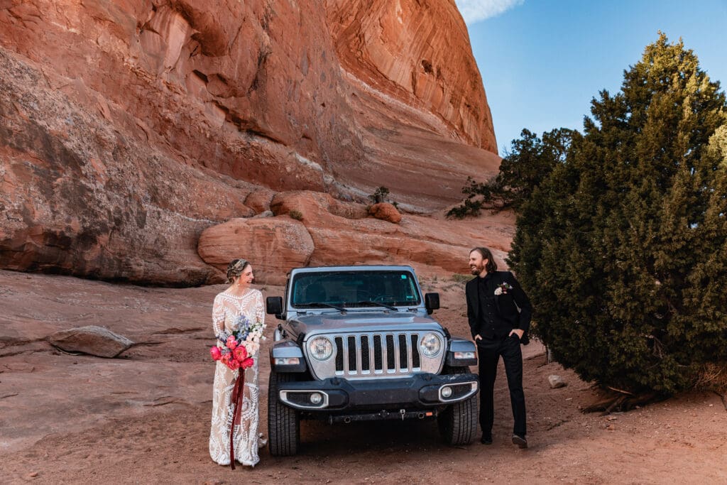 Couple seeing each other for the first time during a Moab elopement first look at Look Glass Arch, surrounded by iconic red rock desert scenery.