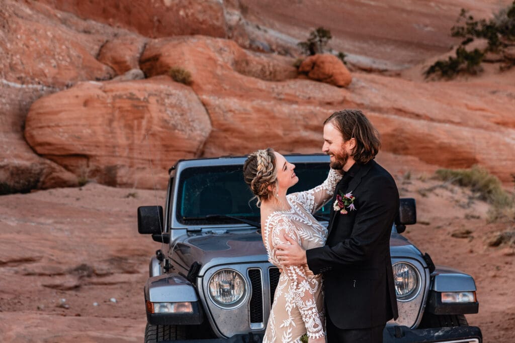Bride tenderly touching her groom’s face during an emotional first look at a Moab elopement at Look Glass Arch, with golden desert light.