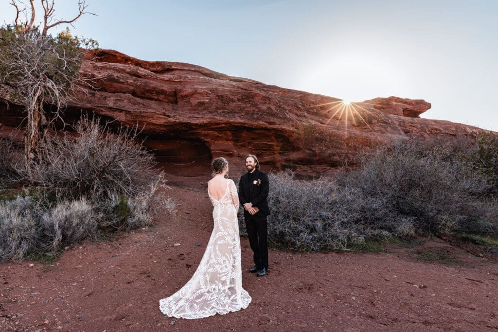 Couple exchanging vows at a Moab elopement during sunset, with dramatic red rock formations in the background and golden desert light illuminating the ceremony.