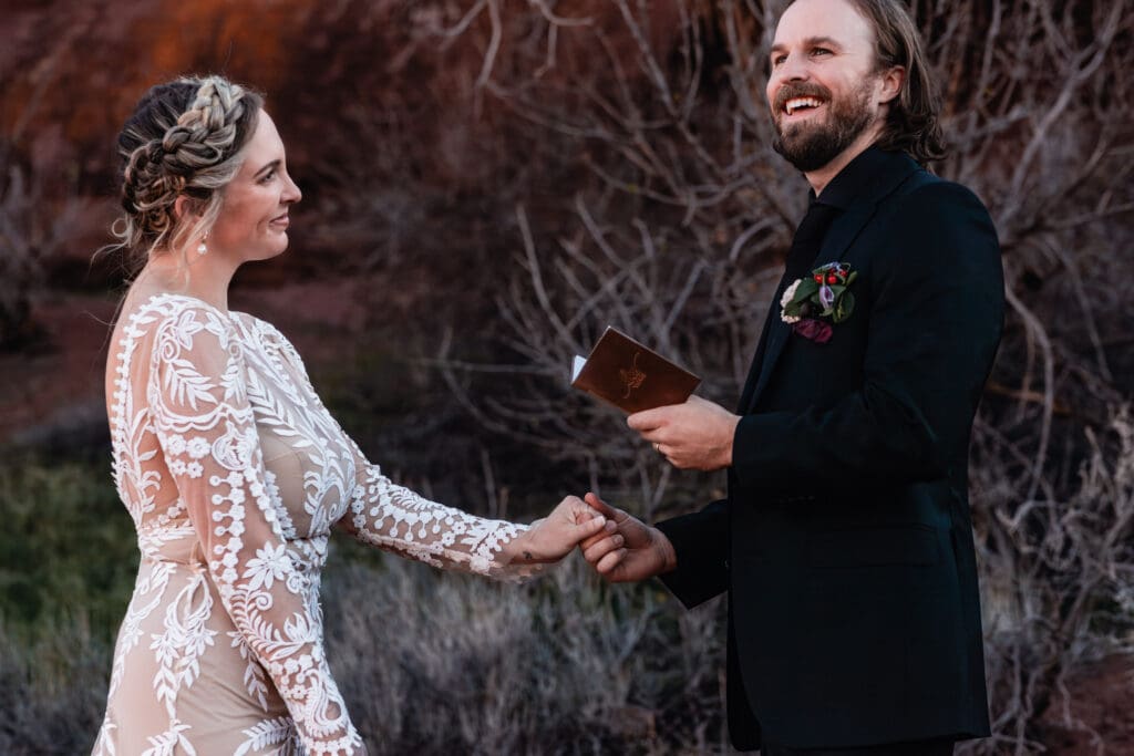 Close-up of a couple holding hands and smiling during their Moab wedding ceremony, capturing intimate and emotional desert elopement moments.