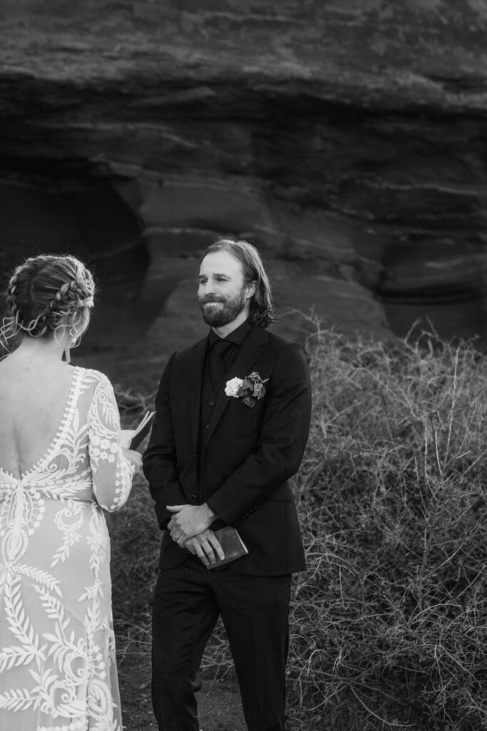 Groom wiping away tears while listening to vows during an intimate Moab elopement ceremony surrounded by red rock desert scenery.