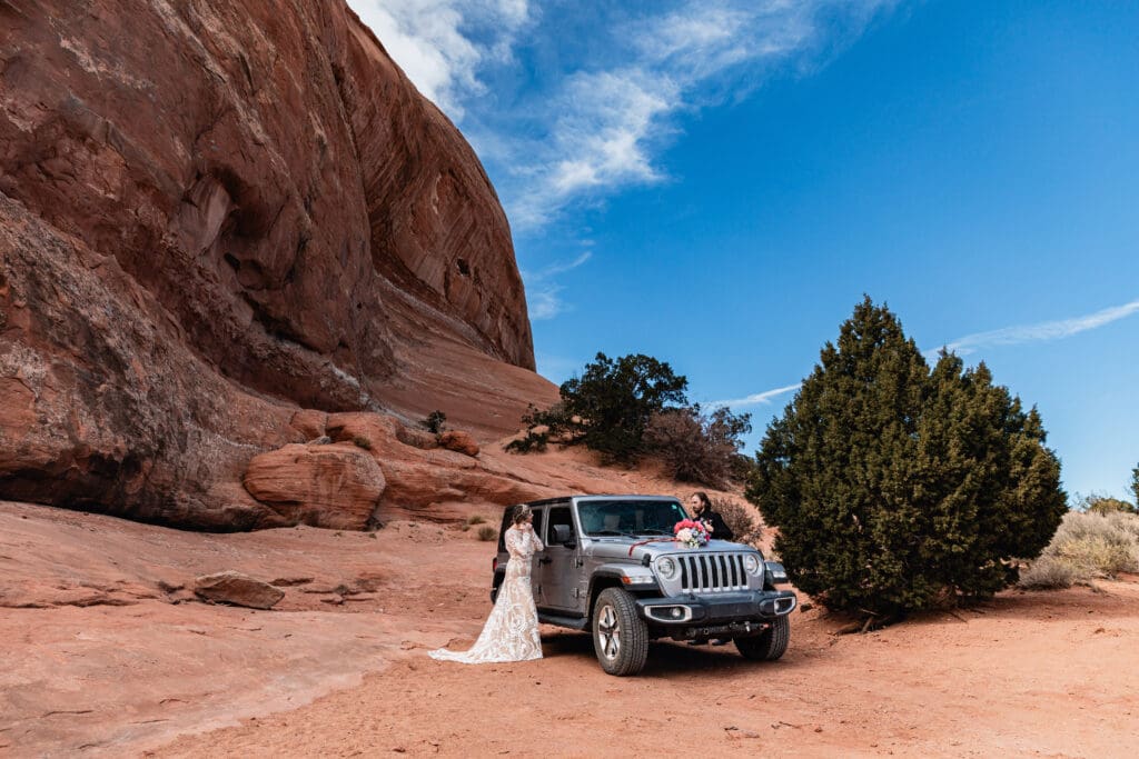 Couple preparing final details on either side of a jeep before their first look during a Moab elopement at Look Glass Arch, capturing intimate wedding moments.