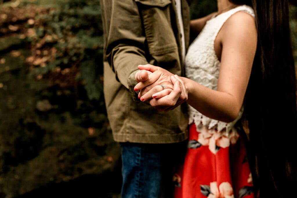 Romantic couple shares a tender moment against a green forest backdrop during an spring engagement session at McConnells Mill State Park