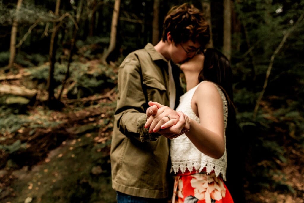 Couple shares an intimate moment together in a lush forest during an outdoor engagement photo session at McConnells Mill State Park
