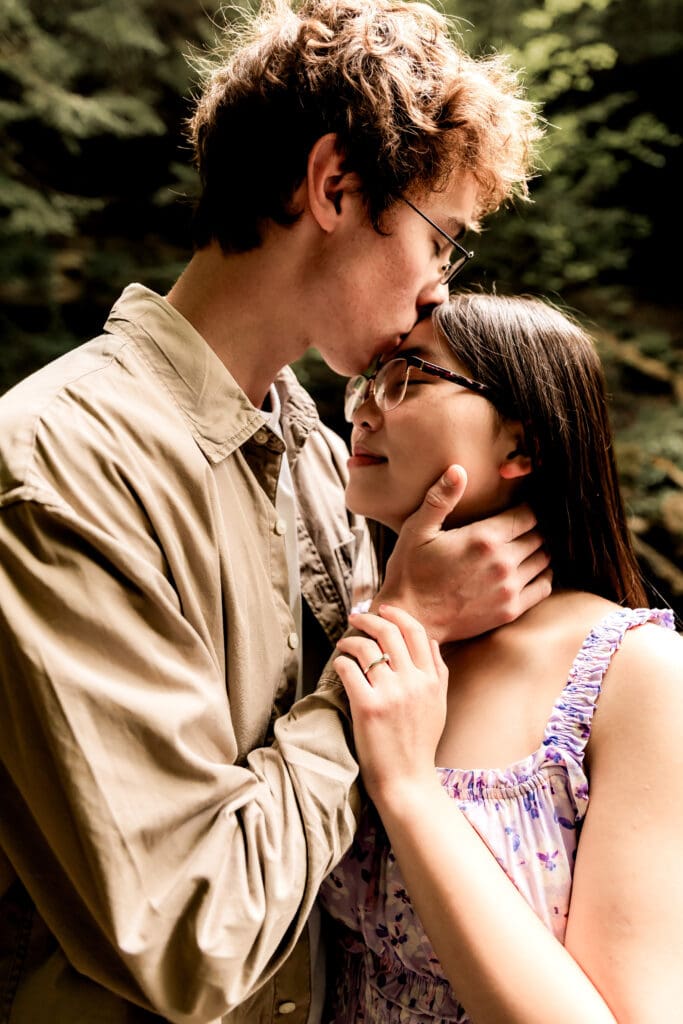 Couple shares a romantic moment in front of a cascading waterfall surrounded by lush forest at McConnells Mill State Park