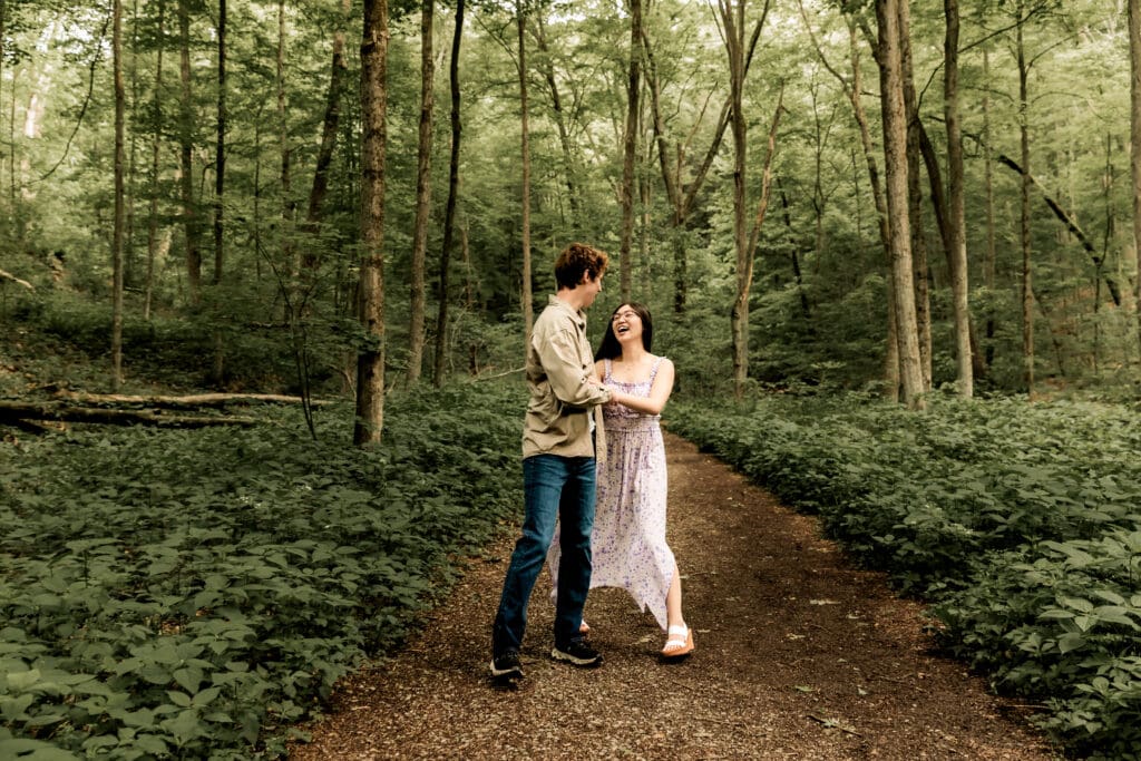 Couple embraces while dancing on a forest path surrounded by lush green foliage at McConnells Mill State Park