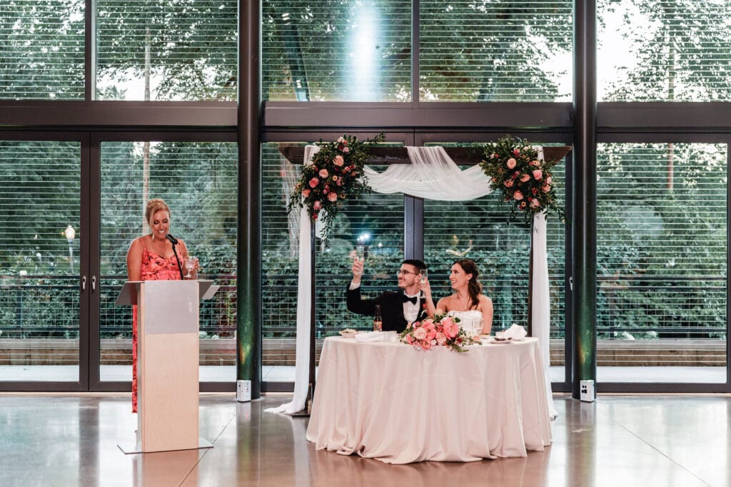 Bride and groom cheering their maid of honor overlooking lush garden greenery at the National Aviary wedding