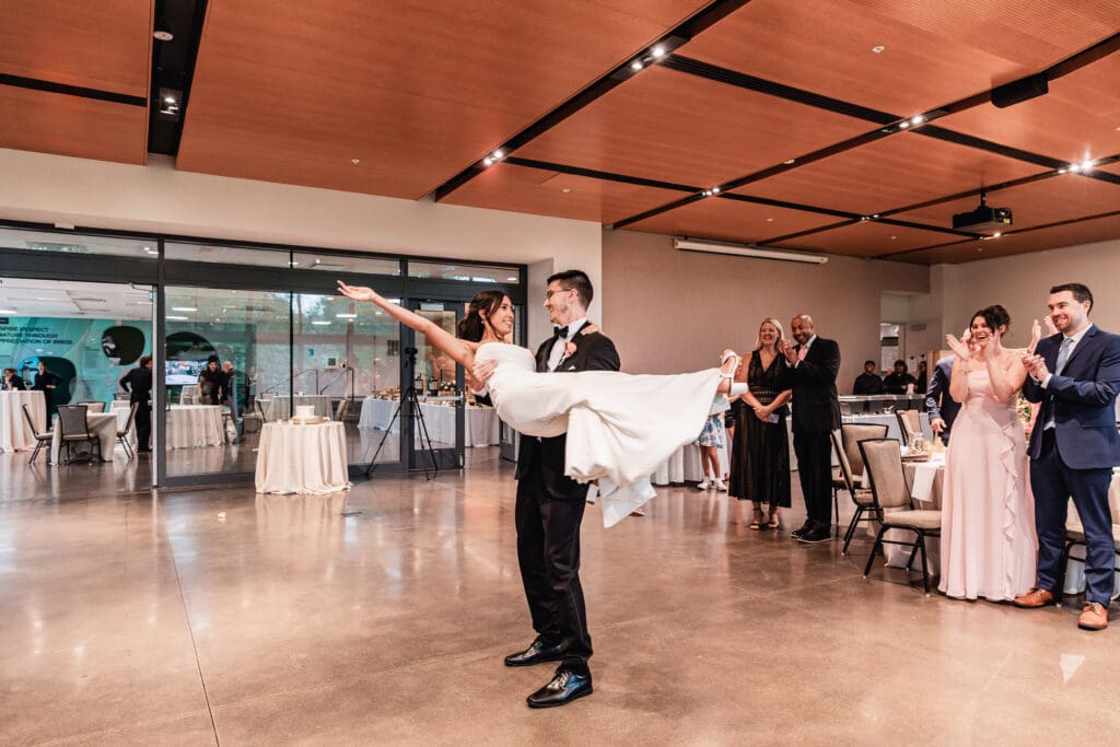 Groom lifting and spinning his bride during first dance at the National Aviary reception
