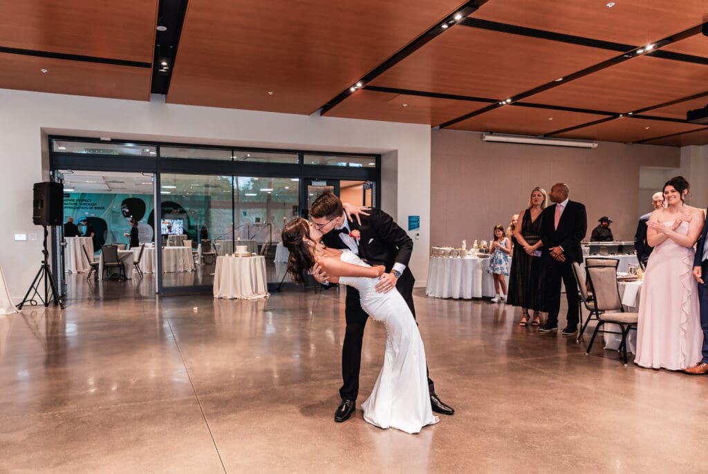 Wedding couple sharing a dip kiss during their first dance at the National Aviary