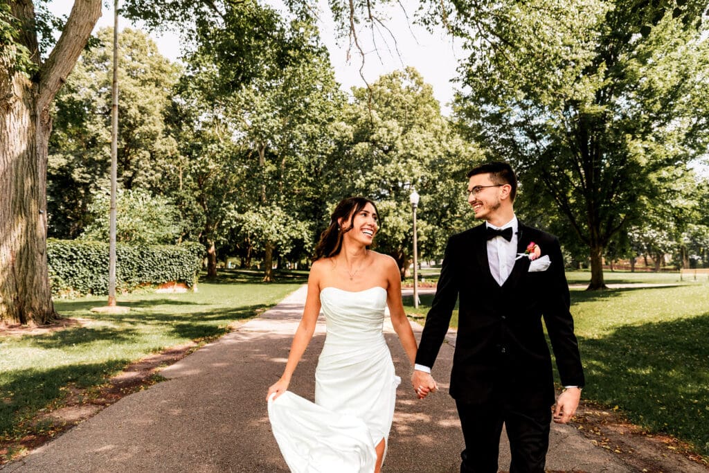 Bride and groom walking and laughing together at Allegheny Commons Park near the National Aviary