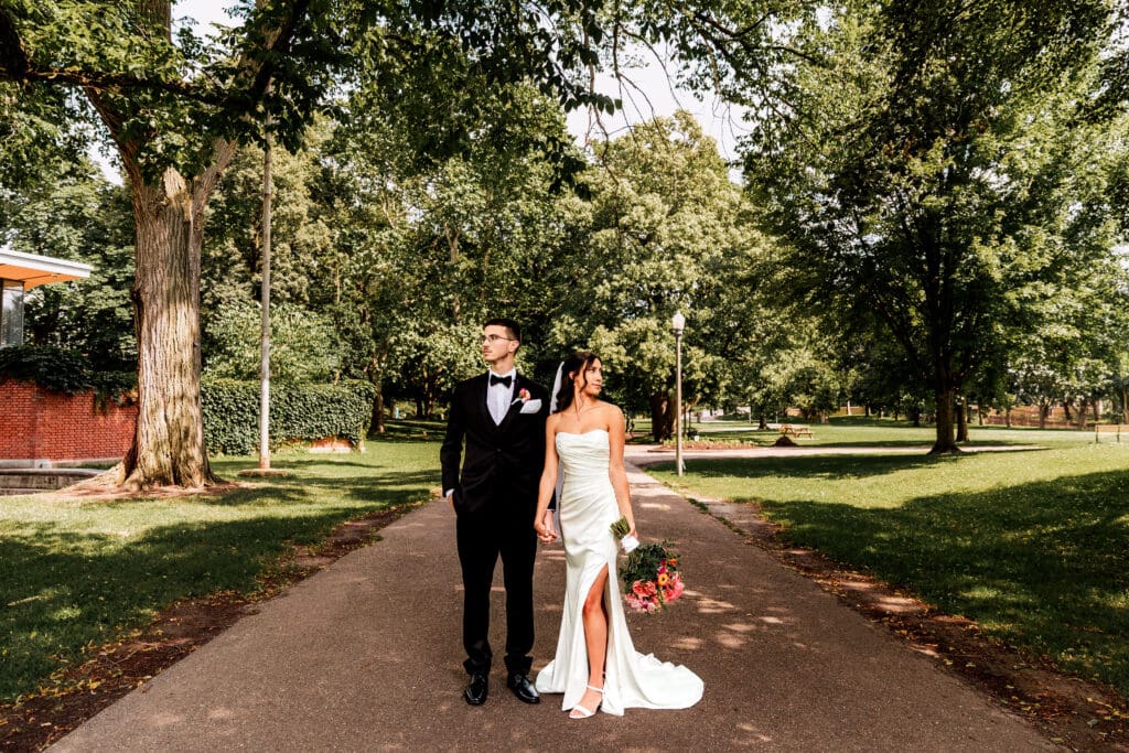 Wedding couple holding hands and looking opposite directions at Allegheny Commons Park near the National Aviary