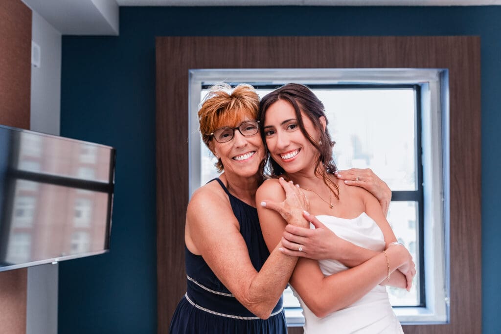 Mother embracing bride after helping her into wedding dress at the National Aviary