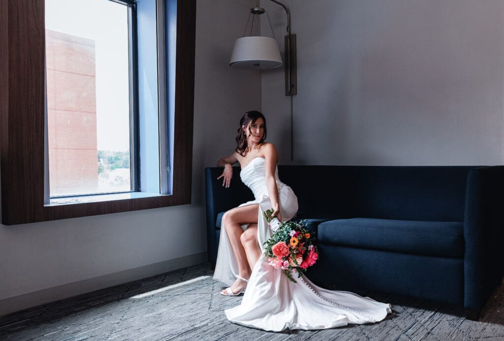 Bride sitting on blue couch holding bouquet during wedding day portraits at the National Aviary