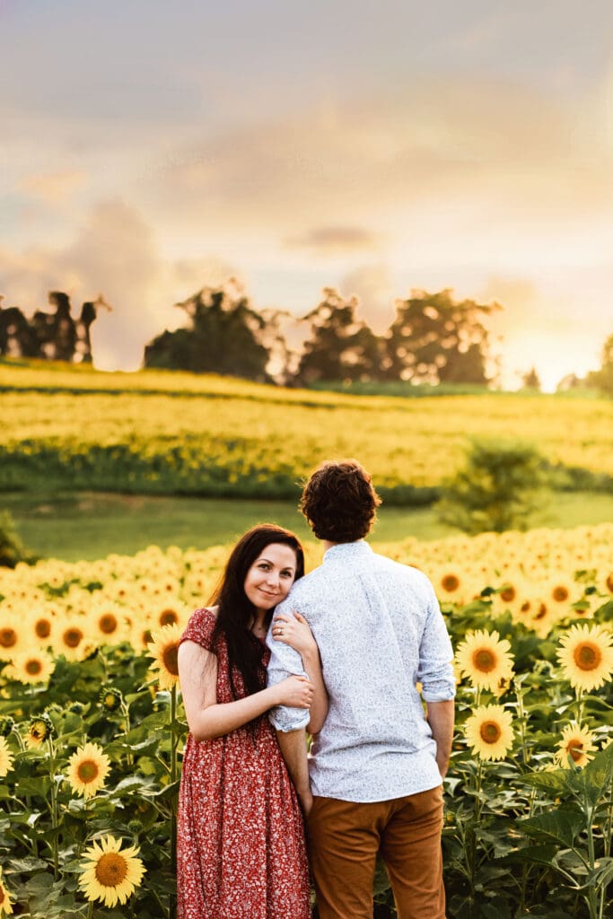 Engagement session of a Pittsburgh couple framed by tall sunflowers at sunset at Schwirian Sunflower Farm