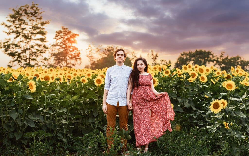 Candid engagement photo of a Pittsburgh couple holding hands in a sunflower field at Schwirian Sunflower Festival
