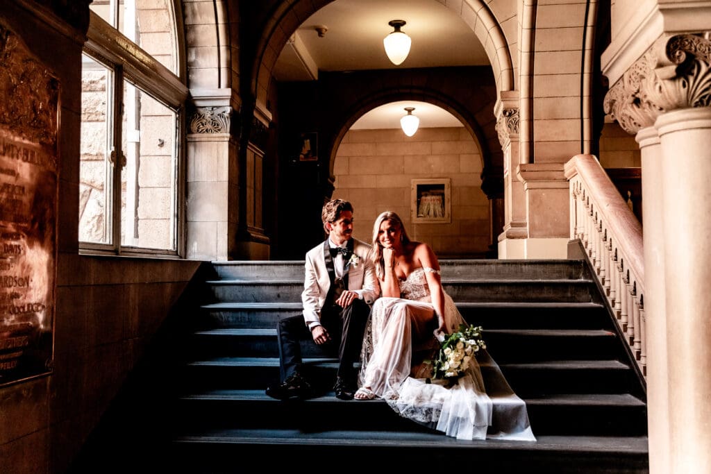 Newly married couple sitting on the stairs inside Allegheny County Courthouse following their wedding ceremony