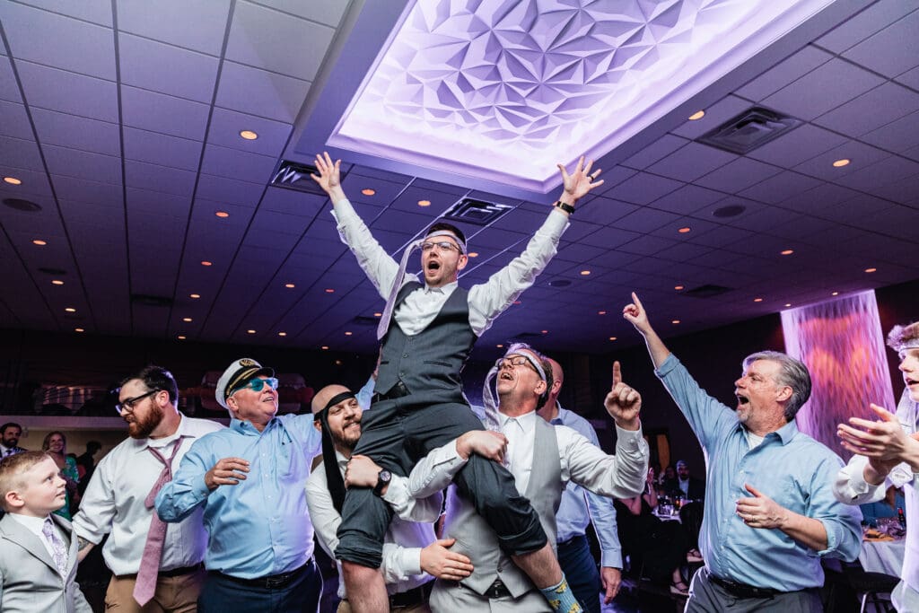 Groom dances with arms raised during reception at The Fez