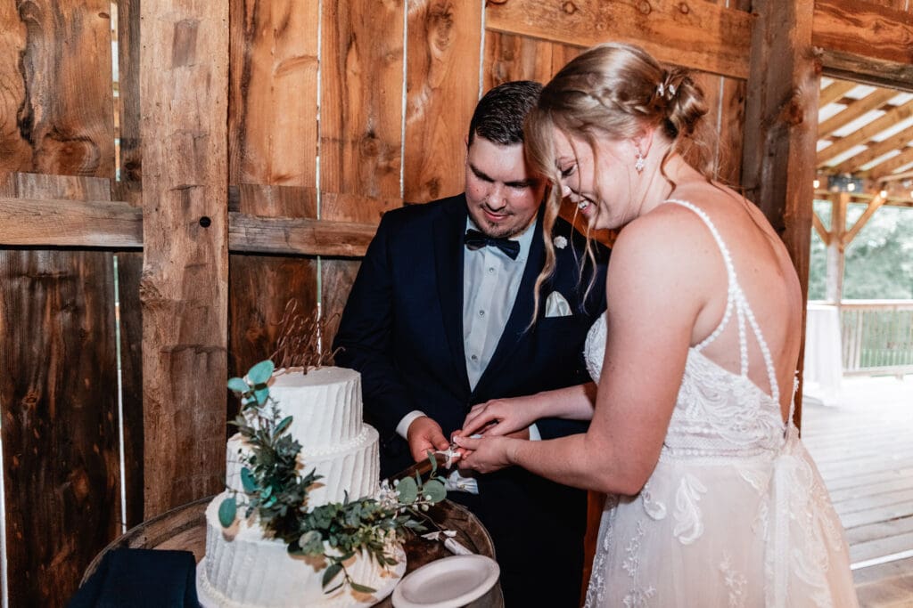 Bride and groom cutting their wedding cake at The Barn at Ever Thine reception in Butler County, PA